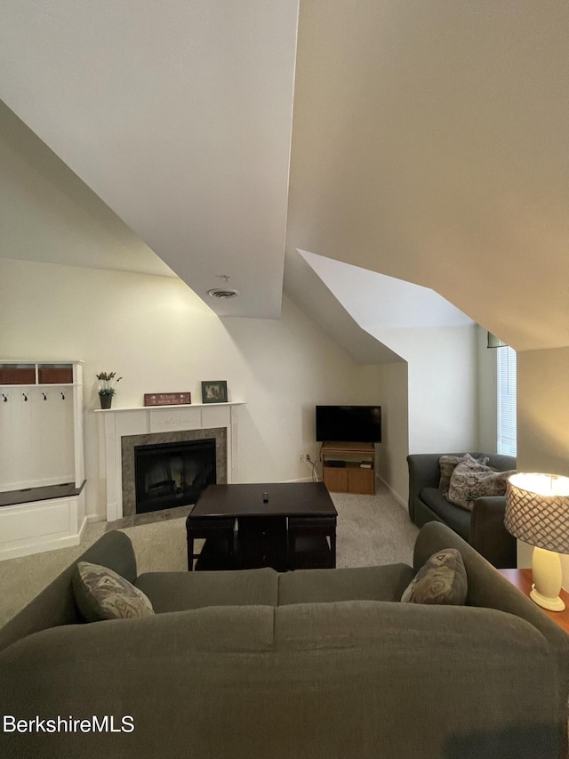 living room with a tiled fireplace, lofted ceiling, and carpet