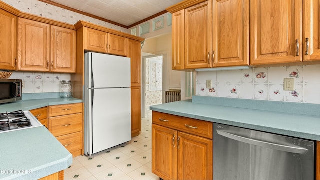 kitchen featuring appliances with stainless steel finishes, light countertops, and ornamental molding