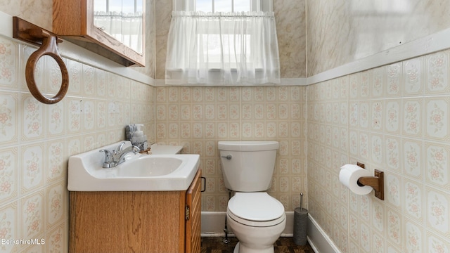 bathroom with a healthy amount of sunlight, toilet, and wallpapered walls