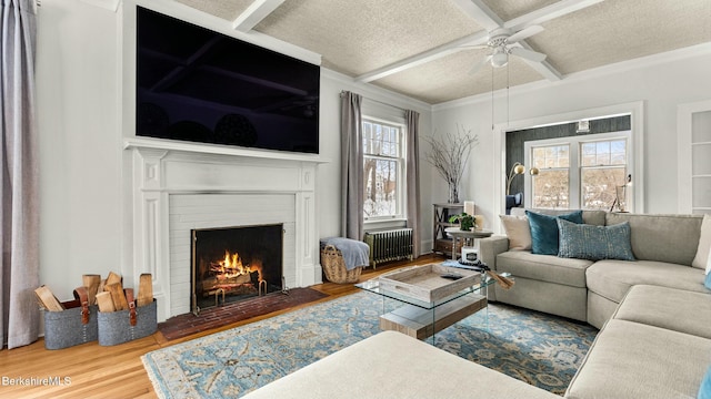 living room featuring a fireplace, radiator heating unit, a textured ceiling, wood finished floors, and coffered ceiling