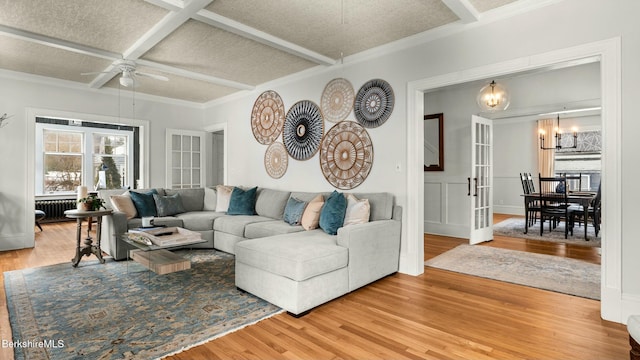 living area featuring french doors, radiator, wood finished floors, coffered ceiling, and ceiling fan with notable chandelier