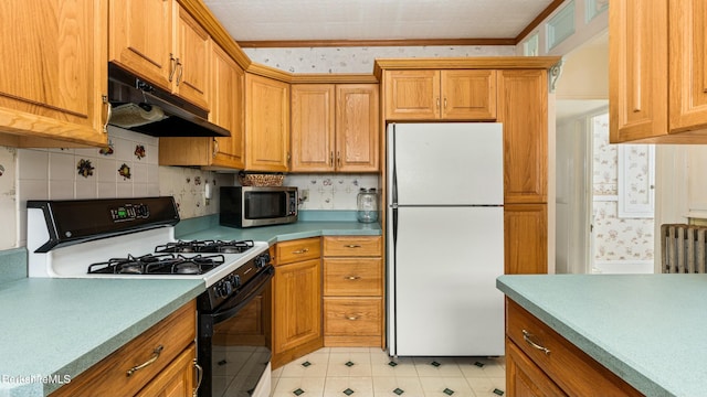 kitchen featuring range with gas cooktop, stainless steel microwave, freestanding refrigerator, under cabinet range hood, and wallpapered walls