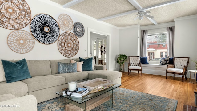 living area with crown molding, a ceiling fan, a textured ceiling, beamed ceiling, and hardwood / wood-style flooring