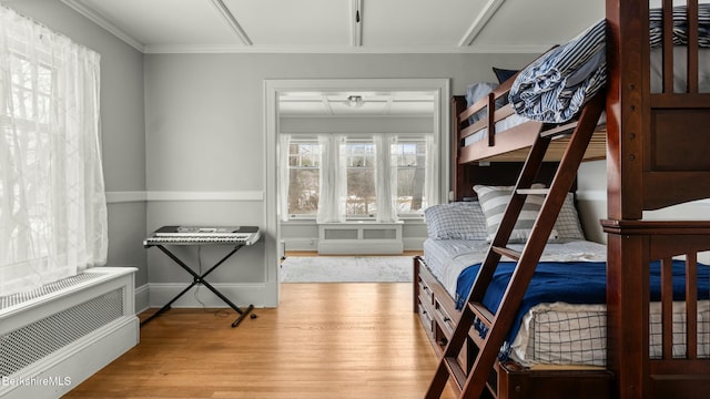 bedroom featuring radiator, crown molding, and wood finished floors