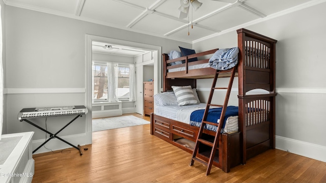 bedroom with baseboards, ornamental molding, and wood finished floors