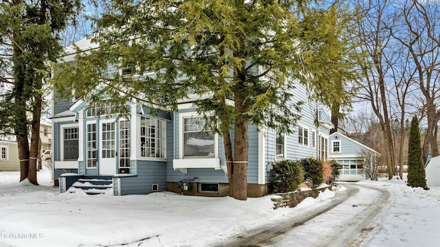 view of front facade featuring entry steps, a detached garage, and a sunroom