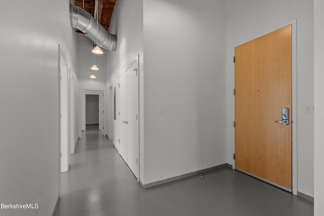 hallway with a towering ceiling and concrete flooring