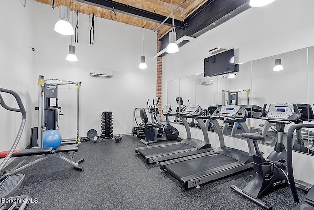 exercise room with a towering ceiling and an AC wall unit