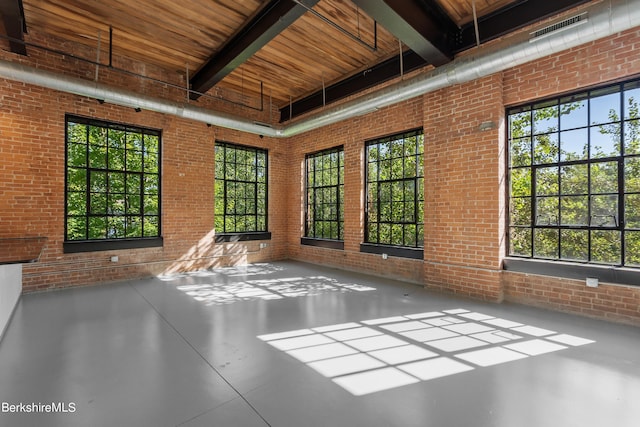 unfurnished sunroom with beam ceiling, plenty of natural light, and wood ceiling