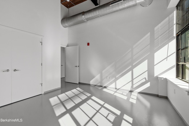 spare room featuring concrete flooring and a high ceiling