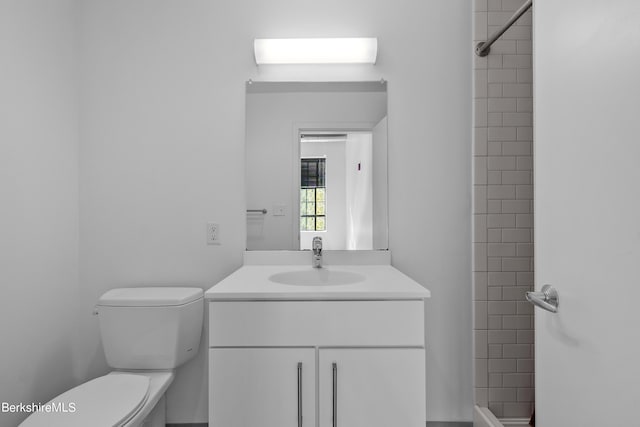 bathroom with toilet, vanity, and tiled shower