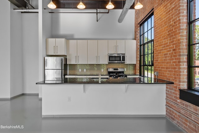 kitchen featuring kitchen peninsula, pendant lighting, dark stone countertops, and stainless steel appliances