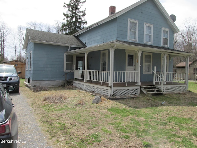 farmhouse featuring a chimney, a front lawn, and covered porch