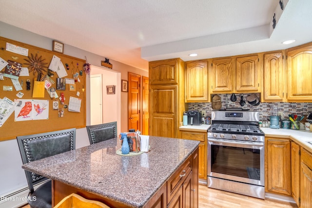 495 Williamstown Rd, Lanesborough, MA 01237 - kitchen featuring stainless steel gas range, backsplash, baseboard heating, a center island, and brown cabinetry