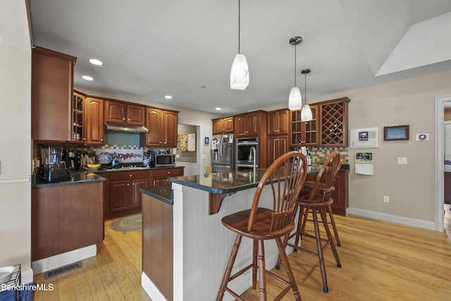 200 Easthampton Rd, Westhampton, MA 01027 - kitchen featuring stainless steel appliances, light wood-style floors, tasteful backsplash, glass insert cabinets, and a breakfast bar