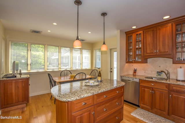 770 Summer St Unit 5D, Lee, MA 01238 - kitchen featuring stainless steel dishwasher, a sink, brown cabinetry, light stone countertops, and light wood-style flooring