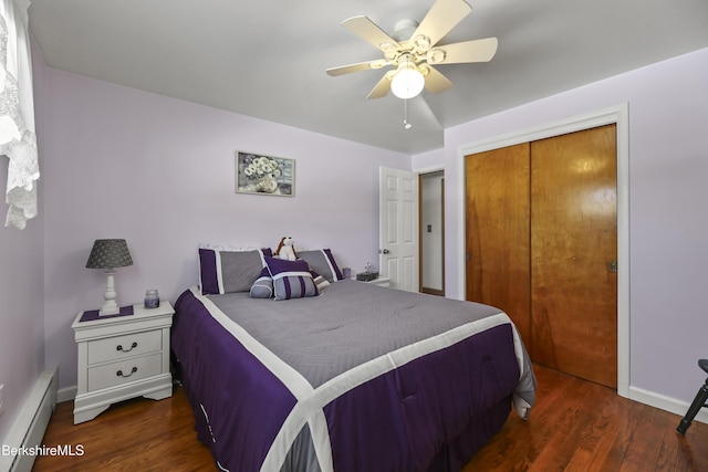 bedroom with a closet, baseboards, baseboard heating, and dark wood-type flooring