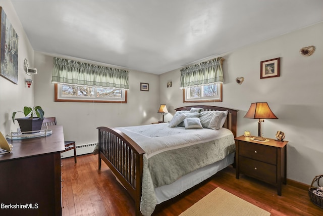 bedroom with a baseboard heating unit, dark wood-style flooring, and baseboards