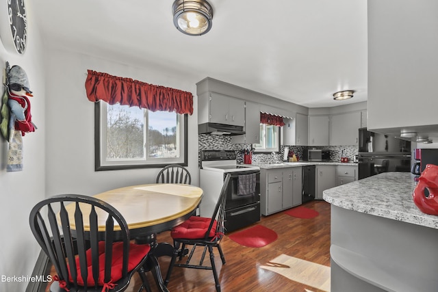 kitchen with black appliances, under cabinet range hood, backsplash, and gray cabinetry