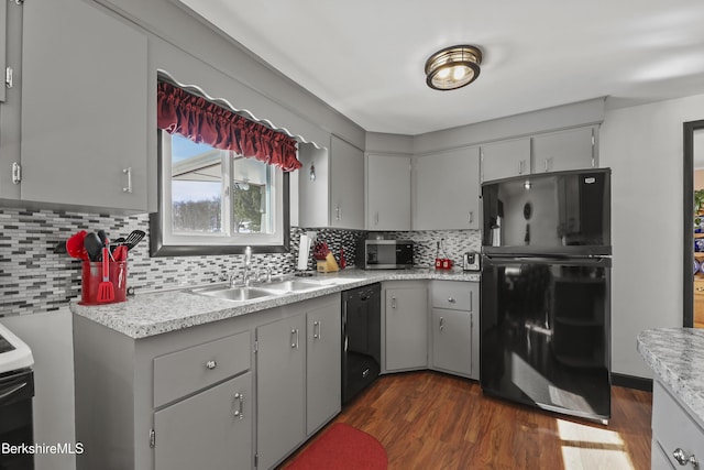 kitchen with tasteful backsplash, dark wood-style floors, light countertops, gray cabinetry, and black appliances