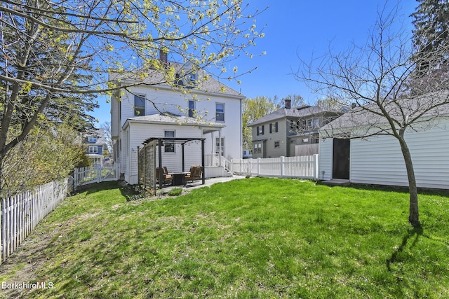 rear view of property with a yard, a chimney, a fenced backyard, and a patio area