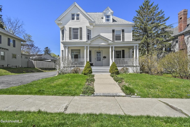 victorian-style house with a porch and a front lawn