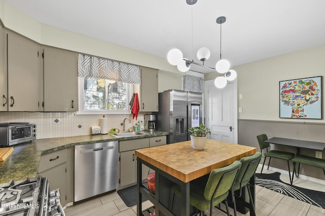 kitchen featuring a sink, a toaster, stainless steel appliances, decorative light fixtures, and tasteful backsplash