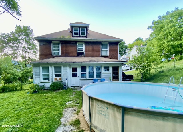 rear view of house featuring a lawn and an outdoor pool