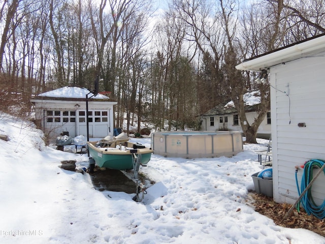 yard covered in snow with an outdoor structure, a garage, and an outdoor pool