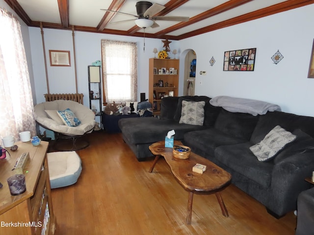 living room featuring arched walkways, radiator heating unit, ceiling fan, and wood finished floors