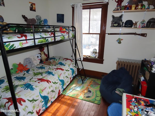 bedroom featuring baseboards, wood-type flooring, and radiator heating unit