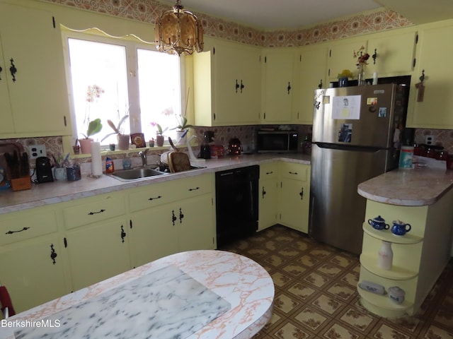 kitchen featuring light countertops, freestanding refrigerator, black dishwasher, and a sink