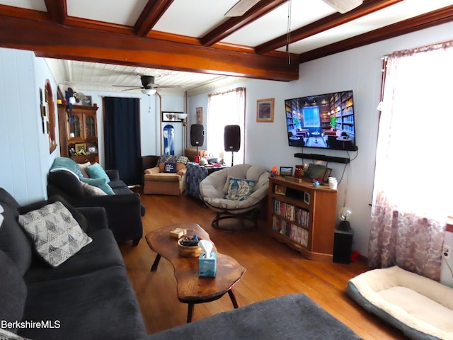 living room featuring beamed ceiling, wood finished floors, and a ceiling fan