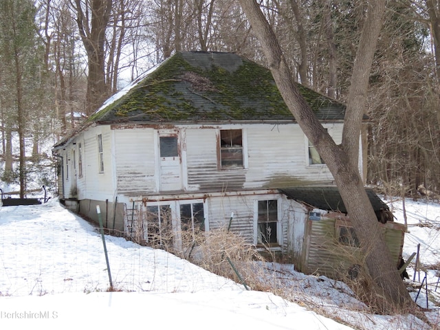 snow covered property with roof with shingles