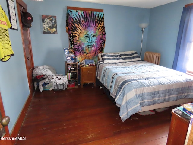 bedroom with radiator heating unit and wood finished floors