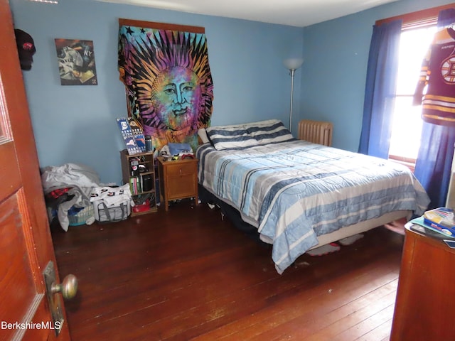 bedroom featuring multiple windows, hardwood / wood-style floors, and radiator heating unit