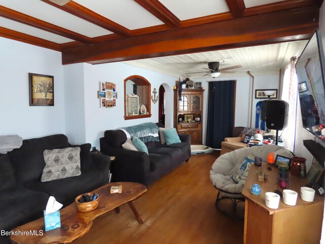 living room with beam ceiling, ornamental molding, wood finished floors, arched walkways, and ceiling fan