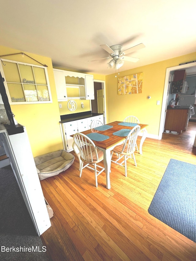 dining area featuring wood-type flooring, a ceiling fan, and baseboards