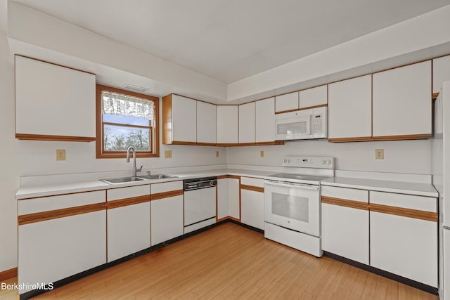 kitchen with white appliances, a sink, light wood-style flooring, and white cabinetry