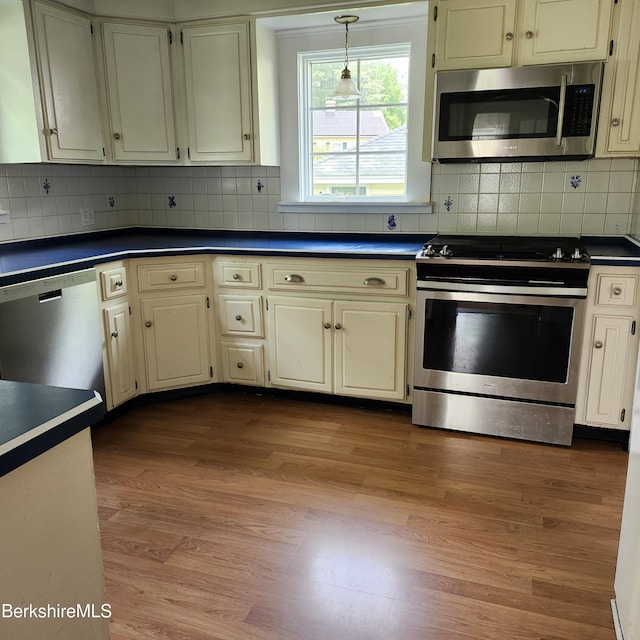 377 Pomeroy Ave, Pittsfield, MA 01201 - kitchen featuring appliances with stainless steel finishes, dark countertops, wood finished floors, decorative light fixtures, and backsplash