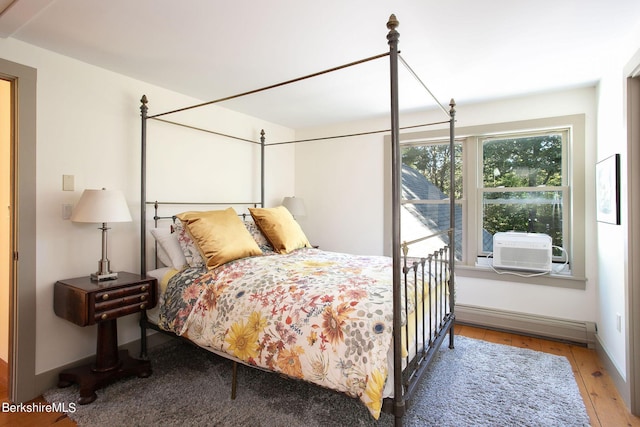 bedroom featuring cooling unit, a baseboard heating unit, and light wood-type flooring