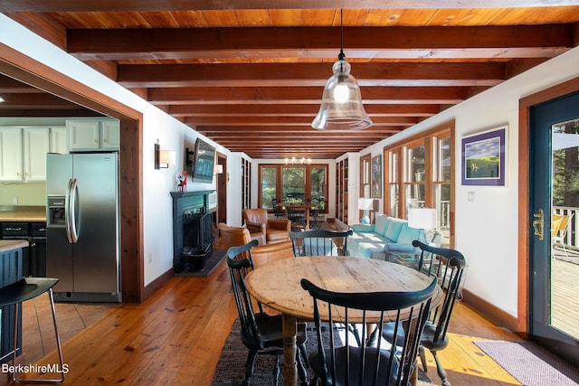 dining room with beam ceiling, wooden ceiling, and light wood-type flooring