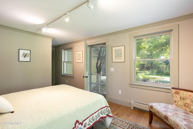 bedroom with rail lighting, wood-type flooring, crown molding, and a baseboard radiator