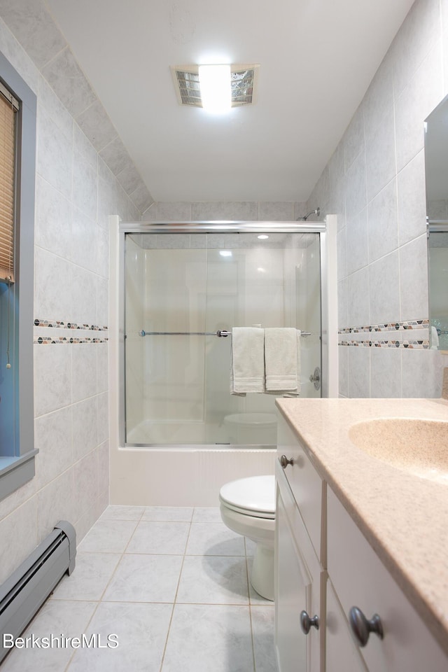 full bathroom with combined bath / shower with glass door, vanity, baseboard heating, tile walls, and toilet