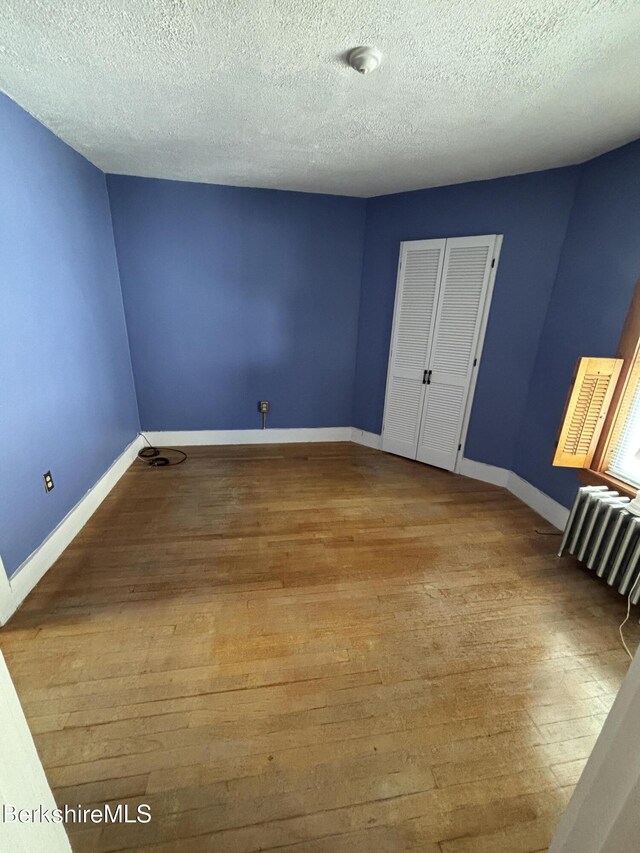 31 Millard Ave, Clarksburg, MA 01247 - empty room featuring hardwood / wood-style floors, radiator, and a textured ceiling