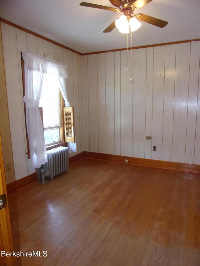 31 Millard Ave, Clarksburg, MA 01247 - spare room with radiator heating unit, wood finished floors, a ceiling fan, wooden walls, and ornamental molding
