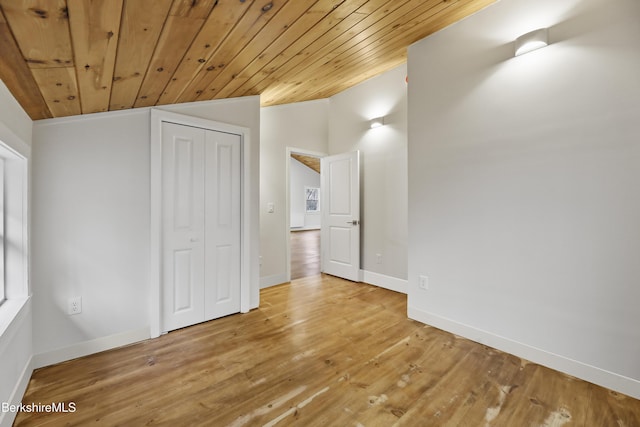 interior space with vaulted ceiling, wood finished floors, a closet, baseboards, and wood ceiling