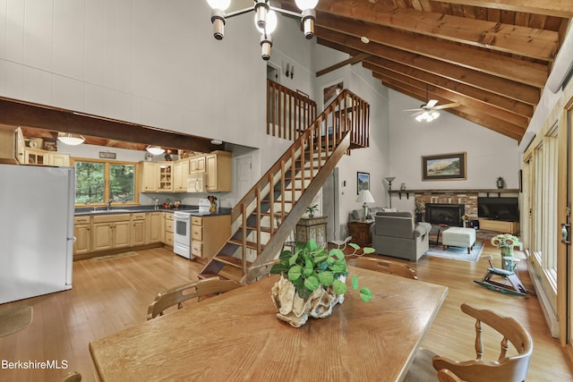 545 Leisure Lee Rd, Lee, MA 01238 - dining space featuring beam ceiling, light wood finished floors, stairway, high vaulted ceiling, and a glass covered fireplace