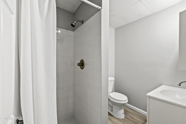 bathroom with toilet, wood finished floors, a shower stall, baseboards, and vanity