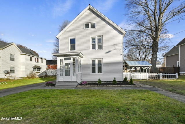 view of front of home featuring entry steps, a front lawn, fence, and a sunroom